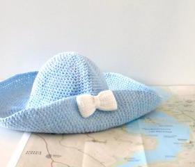 Crochet sun hat with wide brim and bow brooch in sky blue.