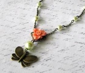 Romantic antiqued bronze butterfly necklace with greenish glass pearls and light orange resin flower