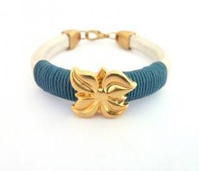  pearl white thick leather bracelet with a gold plated flower charm and dark teal waxed cotton cord details