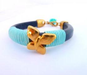 blue thick leather bracelet with a gold plated butterfly and light bue waxed cotton cord